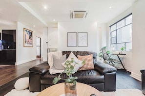 A modern living room with a leather sofa, a coffee table, and a dining area with a table and chairs.
