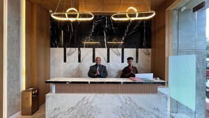 A reception desk with marble countertops and a modern chandelier. - Esquire Hotel Mumbai (Mumbai)