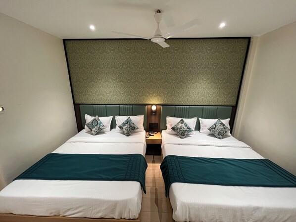 A hotel room with two beds, a ceiling fan, and a patterned wall.
