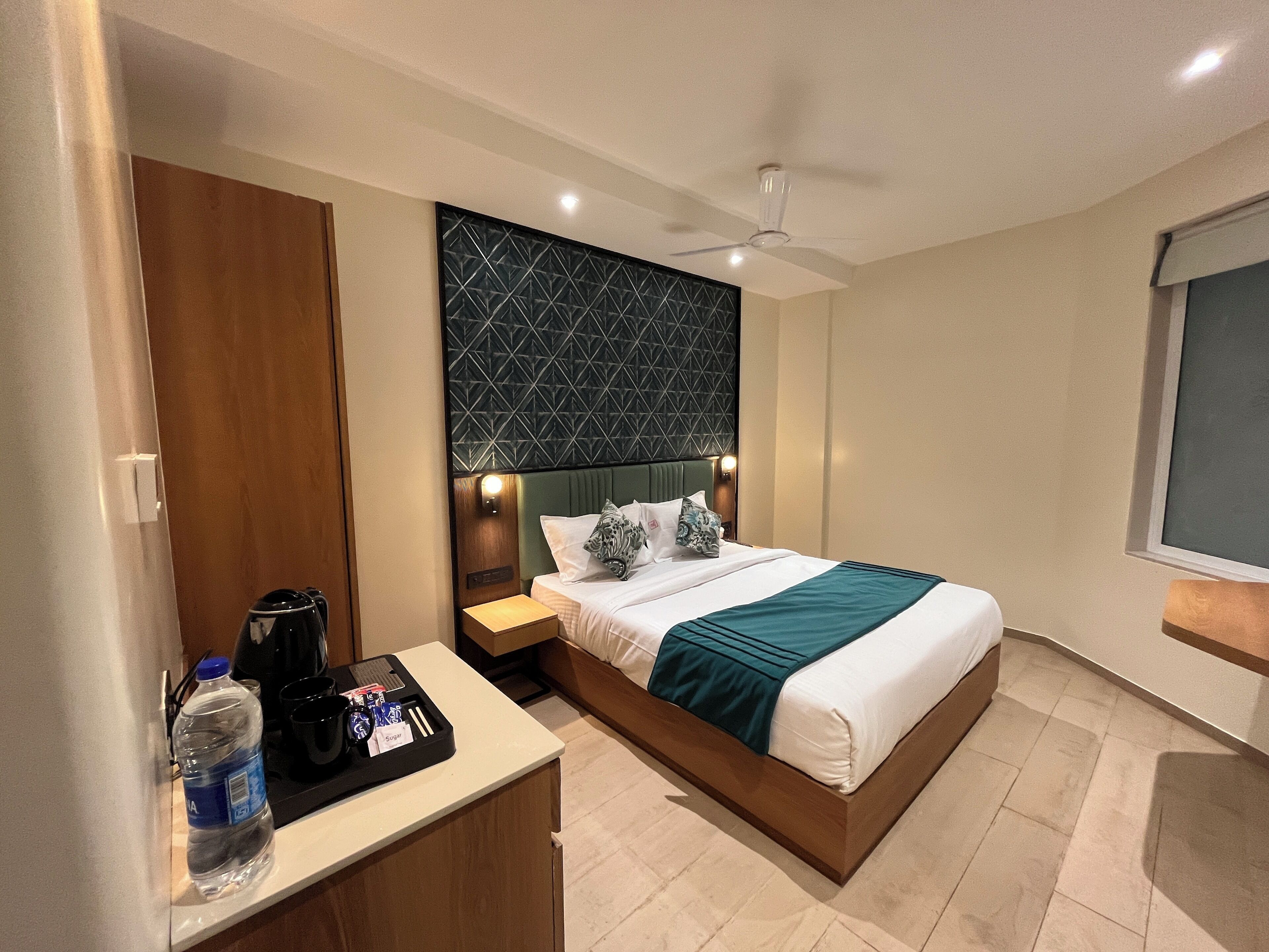 A hotel room with a bed, bedside table, and a ceiling fan.