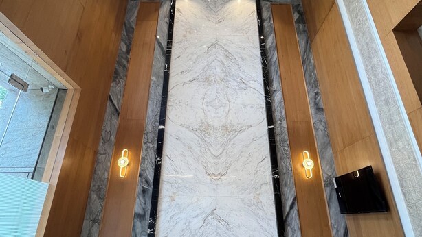A modern interior with a marble wall, wooden paneling, and a unique ceiling light fixture. - Esquire Hotel Mumbai (Mumbai)