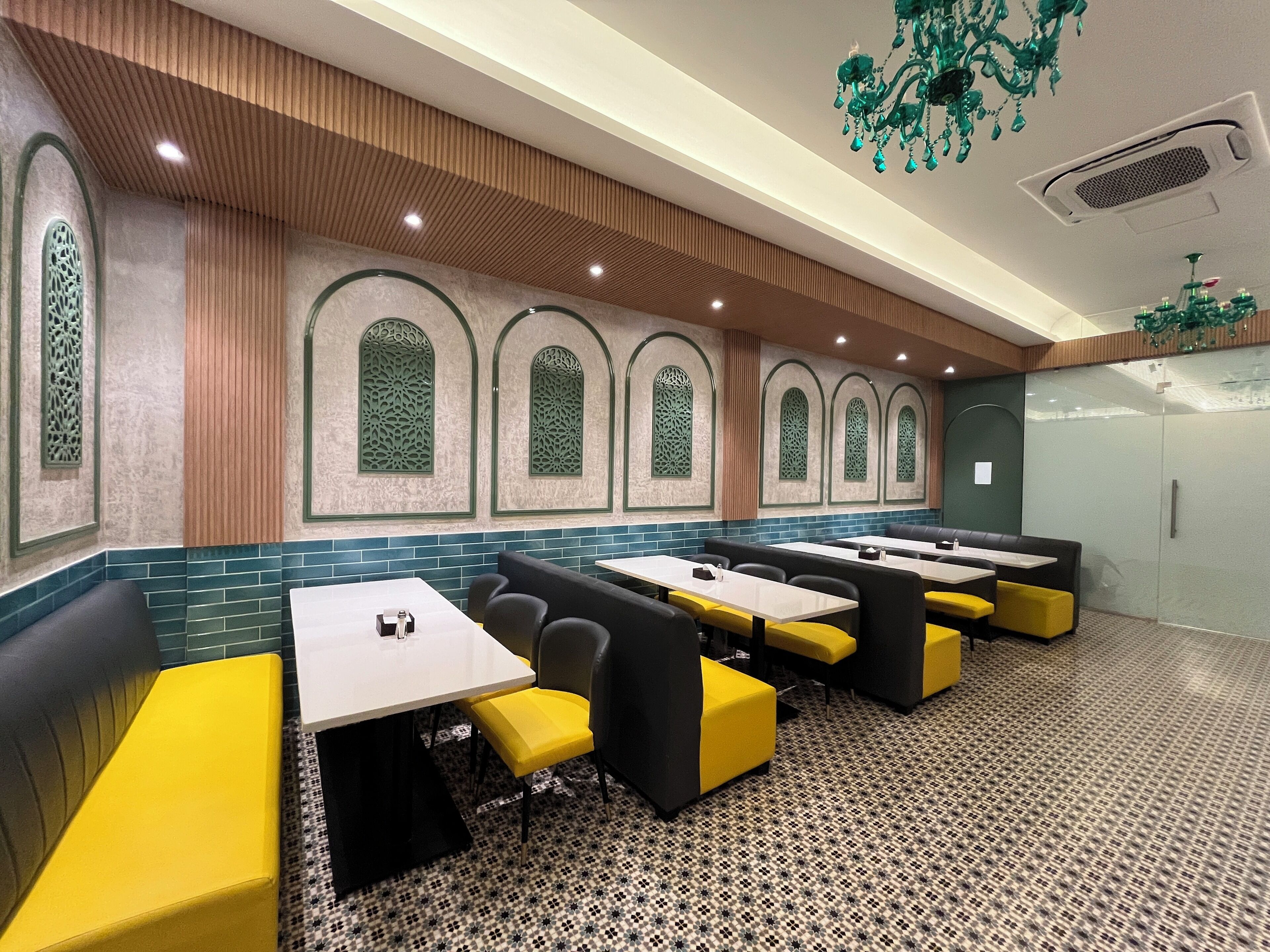 Un restaurante con cabinas y mesas, pisos de baldosas estampadas y ventanas decorativas verdes.