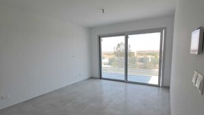 Una habitación amplia y vacía con un gran ventanal corredero que da a un espacio al aire libre.