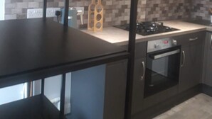 Une cuisine moderne avec des meubles de couleur sombre, un plan de travail noir et un revêtement mural en carreaux.