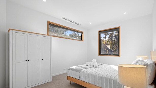 A bedroom with a bed, a wardrobe, a window, and a lamp. - Bimbadeen Bliss (Fairhaven)