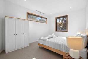 Une chambre à coucher avec un lit, une armoire, une fenêtre et une lampe.