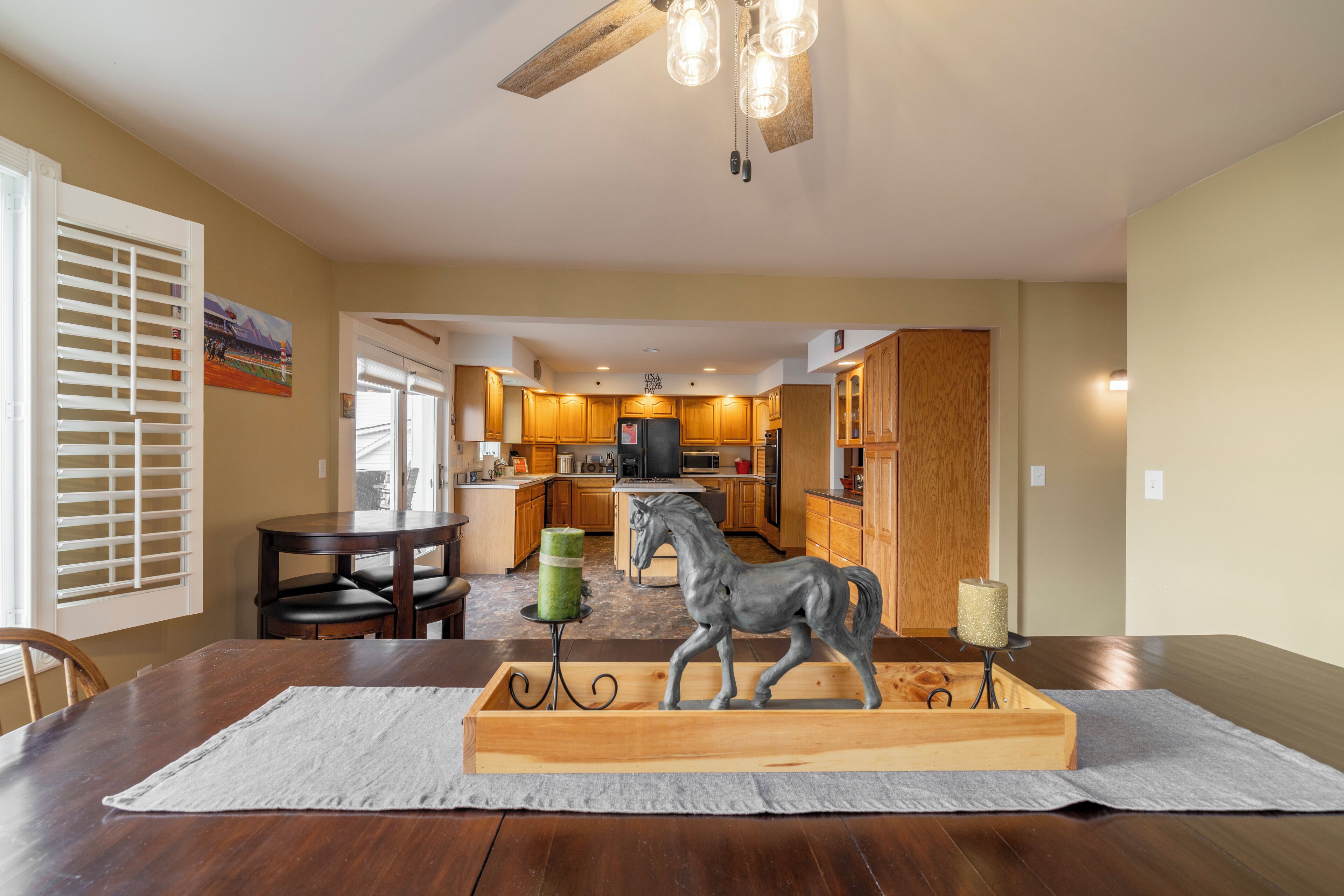 Un comedor con mesa de madera, sillas y una escultura de caballo como centro de mesa.