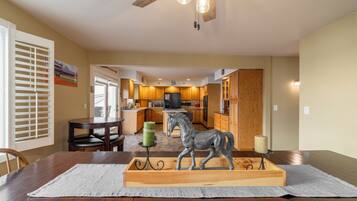 Un comedor con mesa de madera, sillas y una escultura de caballo como centro de mesa.