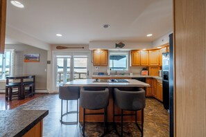 Una cocina moderna con armarios de madera, una isla central con taburetes altos y un refrigerador grande.