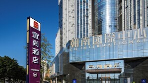 A modern hotel with a prominent CN International sign, large glass windows, and a clear sky. - Yi Shang Hotel Shun Ying Guang Bai (Qingyuan)
