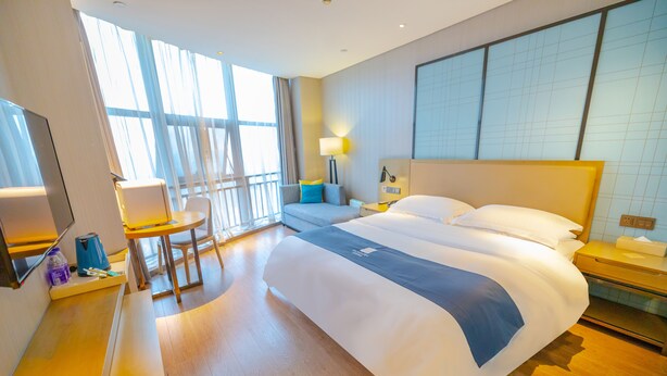 A hotel room with a large bed, a desk, a chair, a TV, and a window with curtains. - Yi Shang Hotel Shun Ying Guang Bai (Qingyuan)
