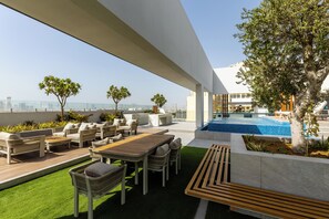 Eine Dachterrasse mit Sitzgelegenheiten im Freien, einem Pool und Blick auf die Stadtlandschaft.