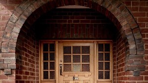 A brick archway with a wooden door featuring a grid pattern window and a small door below. - 'Buckley's Rest' on the doorstep of Battery Point (Battery Point)