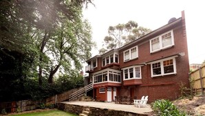 A two-story brick house with a balcony, a stone retaining wall, and a grassy backyard. - 'Buckley's Rest' on the doorstep of Battery Point (Battery Point)