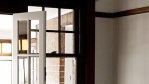 A room with a grey sofa, a white door, and a large window with a view of a brick building. - 'Buckley's Rest' on the doorstep of Battery Point (Battery Point)