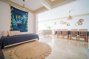 Relax in a spacious room with a large bed, dining area, and vibrant tapestry.