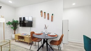 Un espace repas moderne avec une table ronde, deux chaises, un téléviseur et des jardinières fixées au mur.