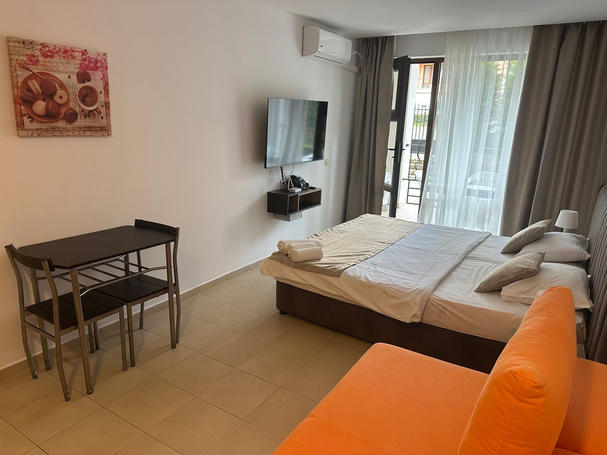 Une chambre d’hôtel avec un lit, un bureau, une chaise, une télévision et une fenêtre avec des rideaux.
