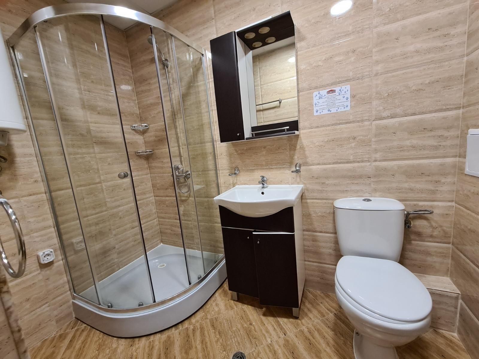 Une salle de bain avec une douche à parois de verre, un lavabo et des toilettes.
