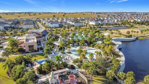 Een resort met een zwembad, palmbomen en uitzicht op het water.