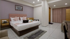 A modern bedroom with a large bed, a desk, and a chair. - Hotel Aurellia (Ahmedabad)