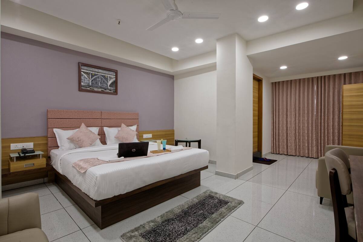 A modern bedroom with a large bed, a desk, and a chair.