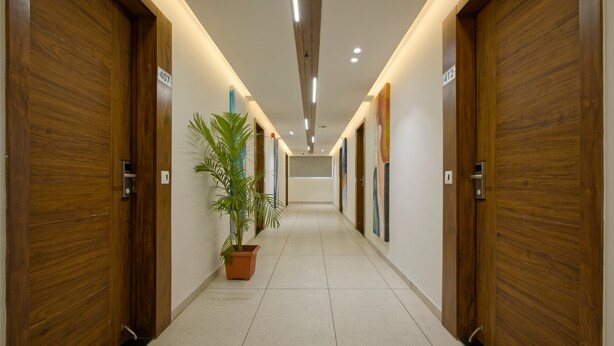 A hallway with wooden doors, numbered 407 and 412, and a potted plant. - Hotel Aurellia (Ahmedabad)