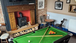 A pool table with a green felt surface, wooden chairs, a fireplace, and framed pictures on the wall. - Holystone Bar and Restaurant  (Newcastle-upon-Tyne)