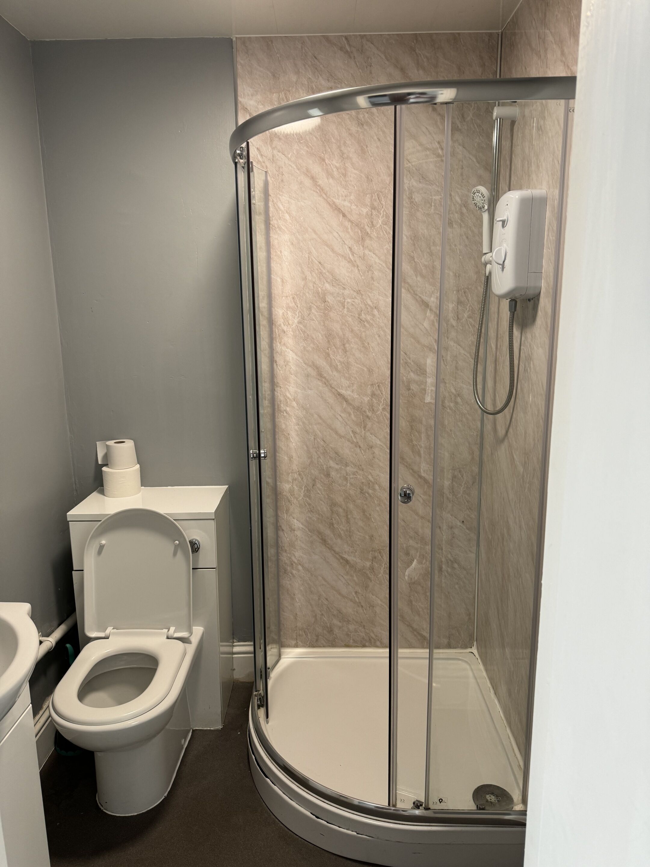 A modern bathroom with a glass-enclosed shower, a toilet, and a sink.
