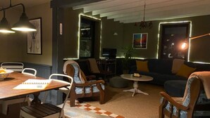 A cozy living area with a dining table, chairs, a sofa, and a small round table.