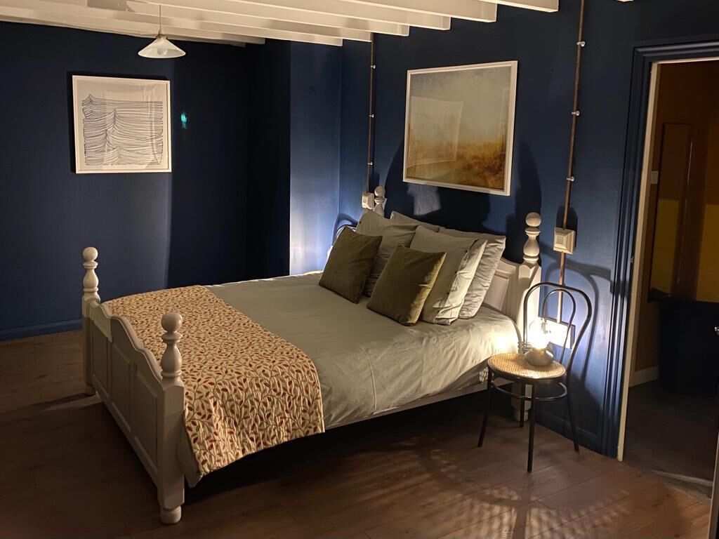 A bedroom with a bed, a chair, and artwork on the walls.