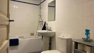 Ein Badezimmer mit Badewanne, Toilette, Waschbecken und Spiegel.