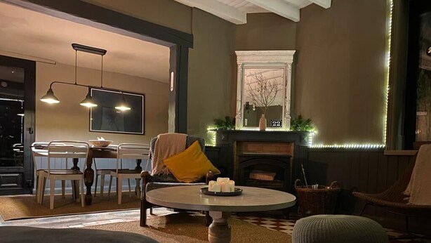 A cozy living room with a fireplace, a dining area, and a large window.