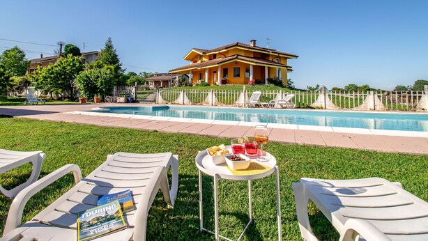 Ein Poolbereich mit Liegestühlen, einem Tisch mit Snacks und Getränken und einem großen Haus im Hintergrund.