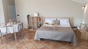 Une chambre à coucher avec un lit, une table de chevet et un coin repas où la table est mise pour le petit-déjeuner.