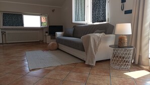 Un salon avec un canapé, une lampe, une petite table et un radiateur.