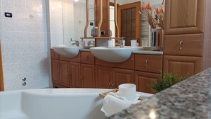 Une salle de bain moderne avec deux lavabos, une baignoire, des meubles en bois et un miroir.