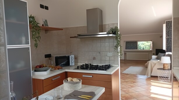 Une cuisine moderne équipée d’un four à micro-ondes, d’une cuisinière et de placards. Un coin repas est aménagé avec une table dressée pour deux personnes.