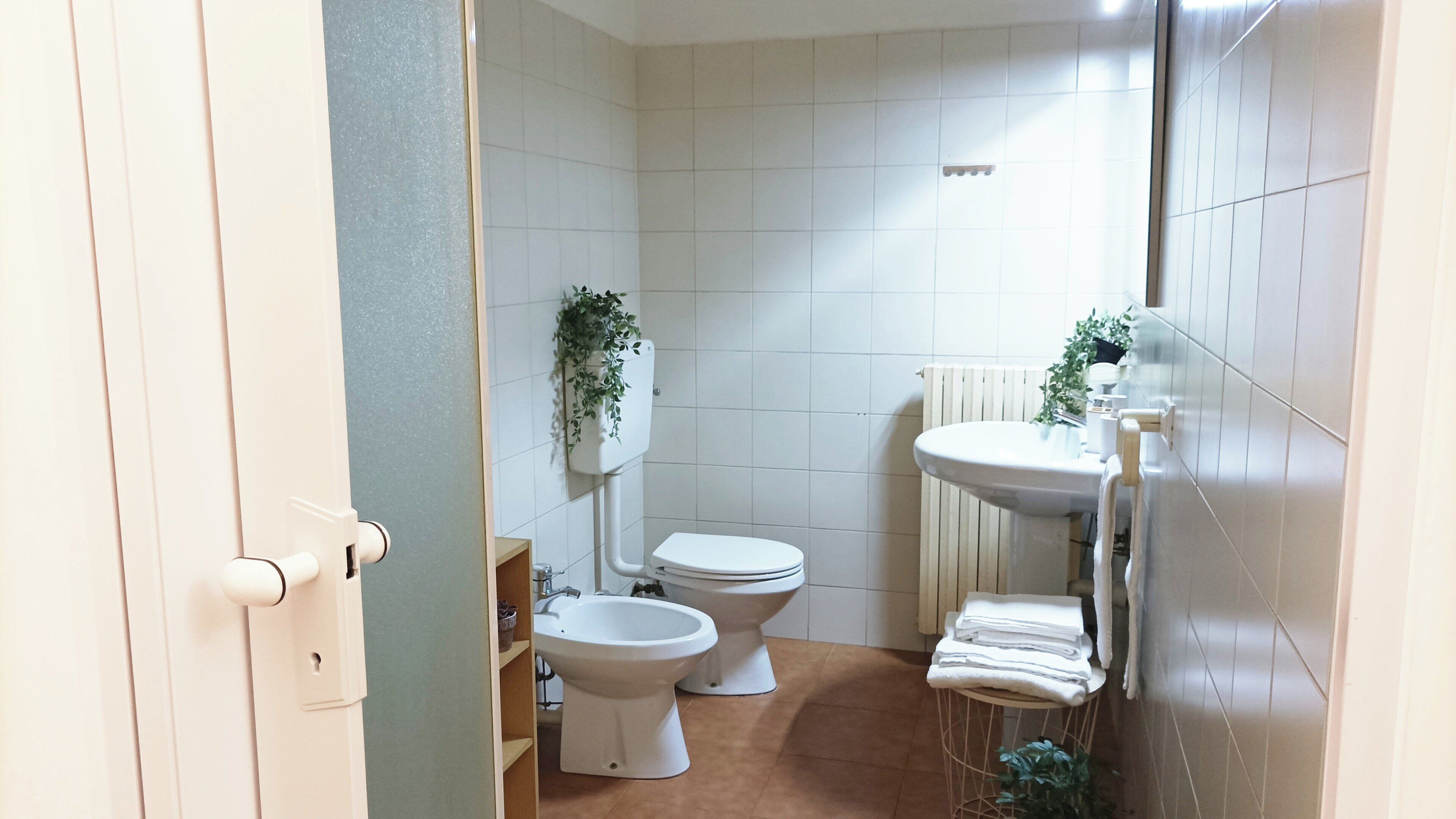 A compact bathroom with a toilet, bidet, and sink.