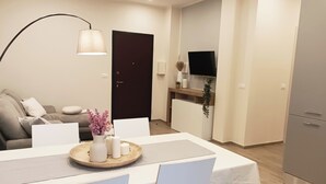 Un salon moderne comprenant un canapé, une table à manger avec des chaises, un téléviseur et un meuble.