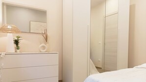 Une chambre à coucher avec un lit, une commode, un miroir et une lampe.