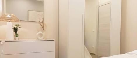 A bedroom with a bed, a dresser, a mirror, and a lamp.