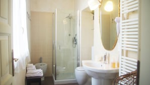 Une salle de bain avec une douche à parois de verre, un lavabo sur colonne et un miroir fixé au mur.