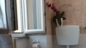 Een badkamer met toilet, bidet en een raam.