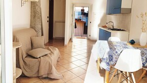 Un accogliente soggiorno con divano, un tavolo da pranzo con sedie, una cucina con pensili e vista sull'ambiente adiacente.