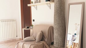 Una camera da letto con un letto, una colonna in pietra, uno specchio e uno scaffale con oggetti decorativi.