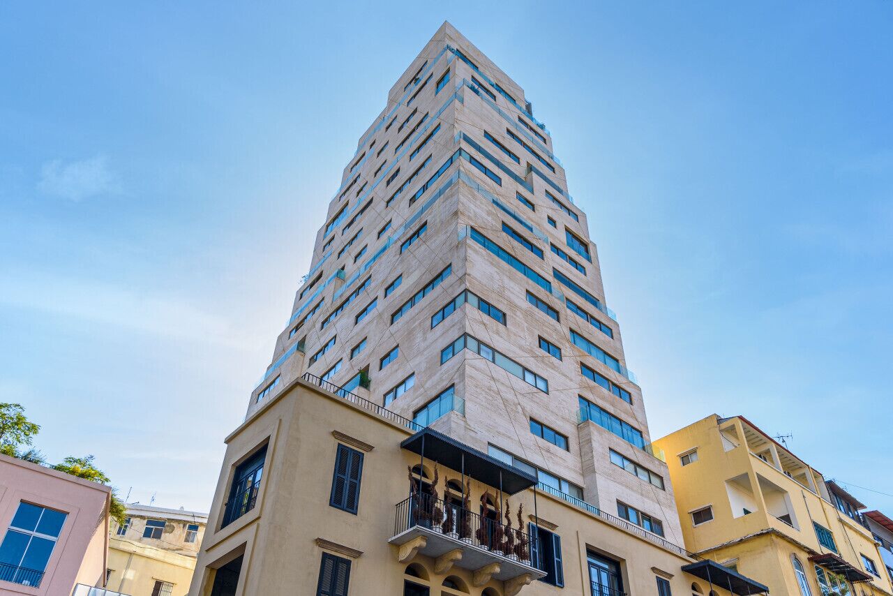 Ein hohes, modernes Gebäude mit einem markanten, winkelförmigen Design, das mehrere Balkone und verschiedene Fensterformen aufweist.