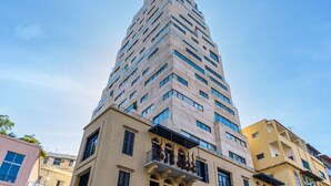 Un edificio alto y moderno con un diseño angular distintivo, con varios balcones y una mezcla de estilos de ventanas.