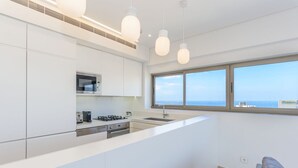 Una cocina moderna con armarios blancos, una isla central e iluminación colgante.