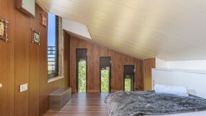 Un dormitorio con paneles de madera, una cama grande y vistas a través de una ventana.